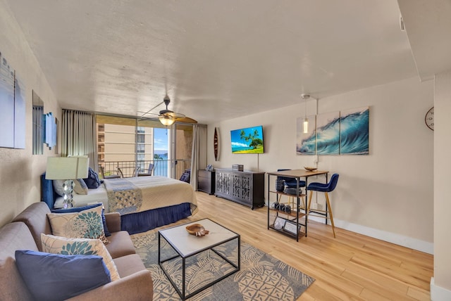 bedroom with access to outside, wood finished floors, a wall of windows, baseboards, and ceiling fan