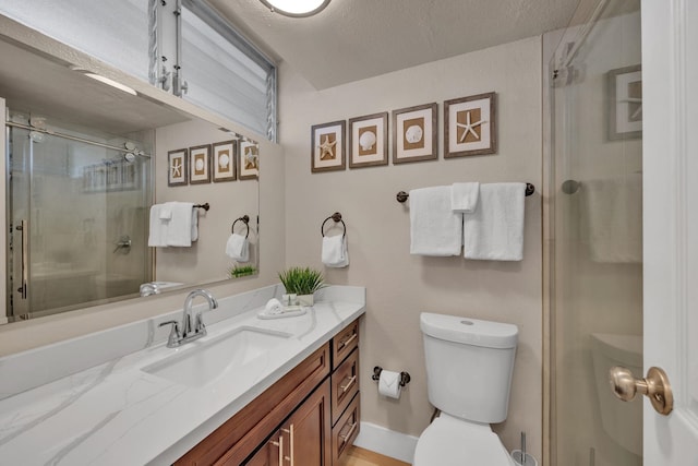 bathroom with toilet, a stall shower, vanity, and a textured ceiling