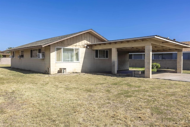 rear view of house with a lawn, cooling unit, a carport, and concrete block siding