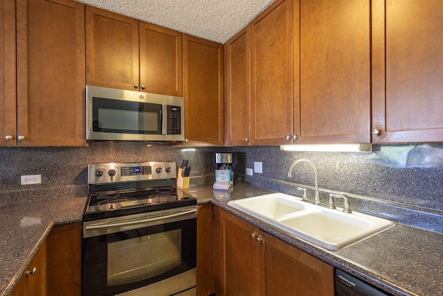 kitchen featuring a textured ceiling, decorative backsplash, sink, and stainless steel appliances