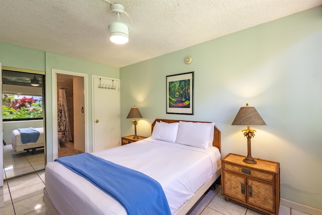 bedroom featuring light tile patterned floors, a textured ceiling, ceiling fan, and connected bathroom