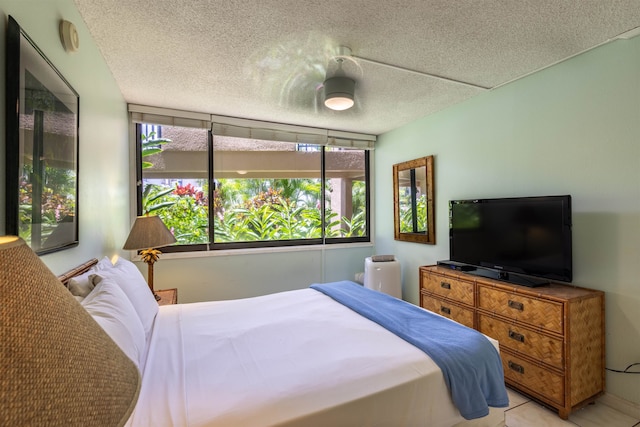 bedroom featuring ceiling fan, light tile patterned floors, and a textured ceiling