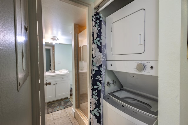 clothes washing area with a textured ceiling, light tile patterned flooring, and stacked washer / drying machine