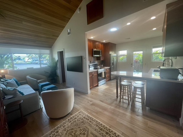 living room featuring high vaulted ceiling, light wood-style flooring, recessed lighting, visible vents, and baseboards