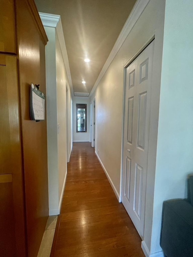 hallway featuring baseboards, crown molding, and wood finished floors