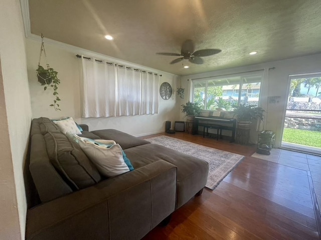 living area featuring a ceiling fan, dark wood-style flooring, a healthy amount of sunlight, and a textured ceiling