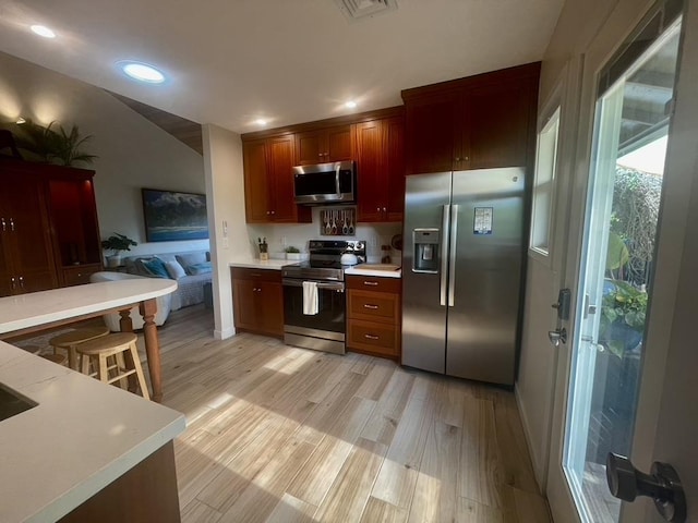 kitchen with recessed lighting, stainless steel appliances, visible vents, light wood-style floors, and light countertops