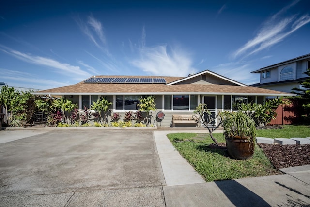 view of front facade with a shingled roof and roof mounted solar panels