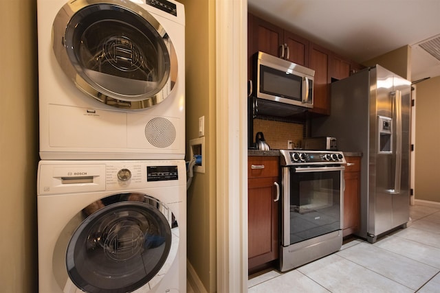 washroom featuring light tile patterned floors and stacked washing maching and dryer