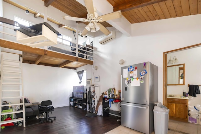 kitchen featuring a wall mounted AC, stainless steel refrigerator, a towering ceiling, hardwood / wood-style flooring, and ceiling fan