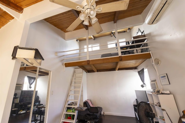 interior space featuring beam ceiling, a wall unit AC, wooden ceiling, and ceiling fan