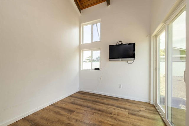 empty room with wood-type flooring, a healthy amount of sunlight, wood ceiling, and beam ceiling