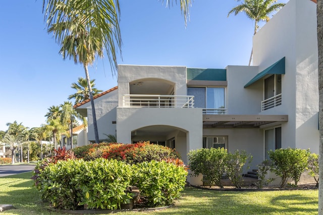 view of front facade featuring a front lawn and a balcony