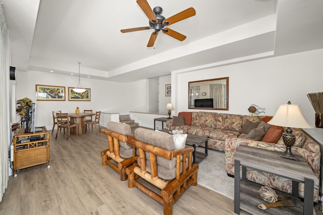 living room with a tray ceiling, light hardwood / wood-style flooring, and ceiling fan