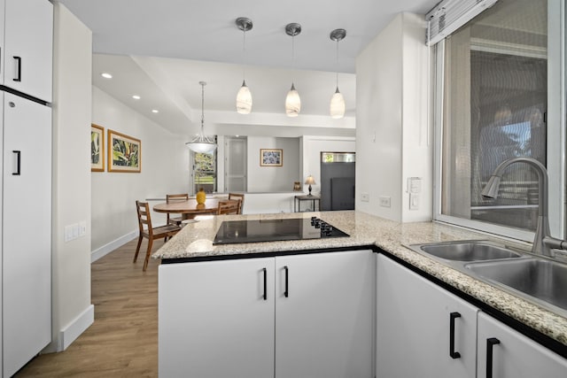 kitchen featuring white cabinetry, black electric stovetop, pendant lighting, and white fridge