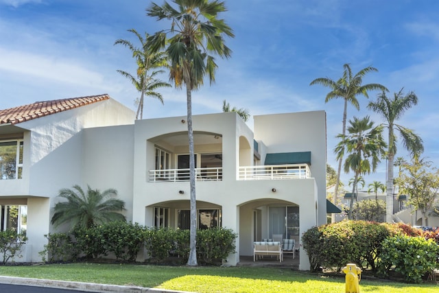 back of property with a balcony and a lawn