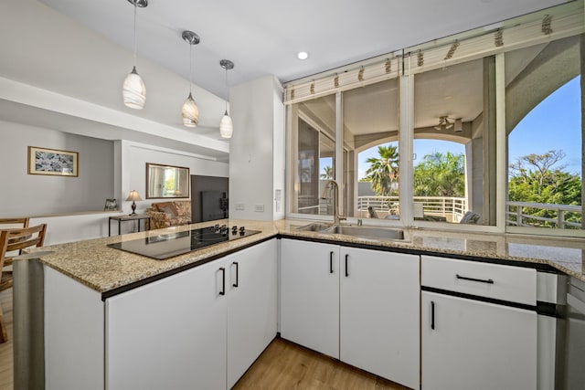 kitchen with pendant lighting, white cabinetry, sink, light stone counters, and black electric cooktop