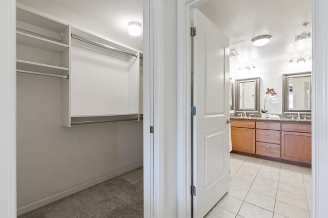 bathroom featuring double vanity, tile patterned floors, baseboards, and a sink
