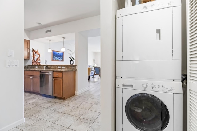 laundry area featuring visible vents, a sink, stacked washing maching and dryer, and baseboards