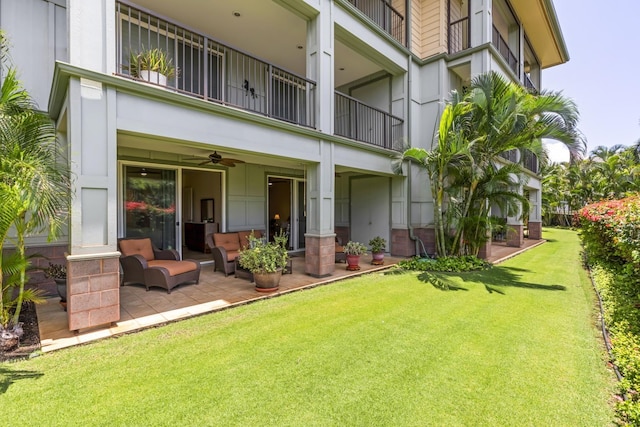 back of house featuring a balcony, a patio, outdoor lounge area, ceiling fan, and a yard