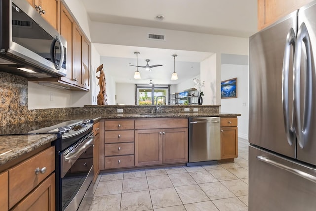 kitchen featuring a sink, appliances with stainless steel finishes, visible vents, brown cabinetry, and backsplash
