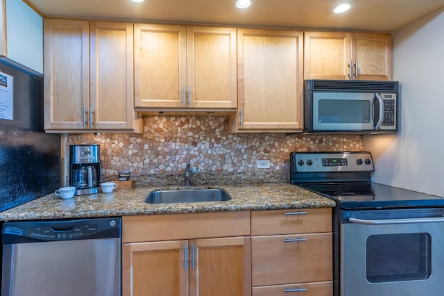 kitchen with light brown cabinetry, stainless steel appliances, backsplash, a sink, and stone countertops