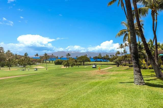 surrounding community with view of golf course, a mountain view, and a lawn