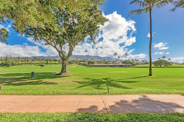 view of property's community with a mountain view, golf course view, and a lawn