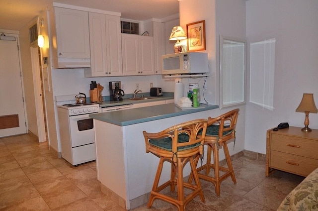 kitchen featuring a kitchen bar, white cabinetry, and white appliances