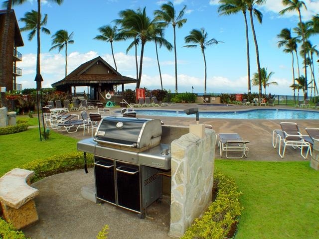 view of property's community with a swimming pool, a patio area, and a lawn