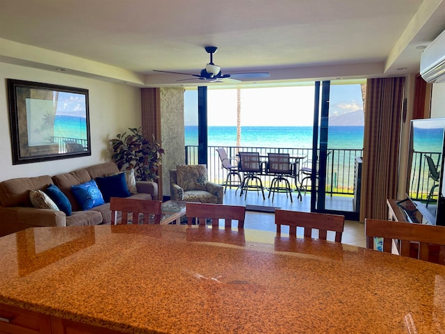 tiled living room featuring ceiling fan, an AC wall unit, and a water view