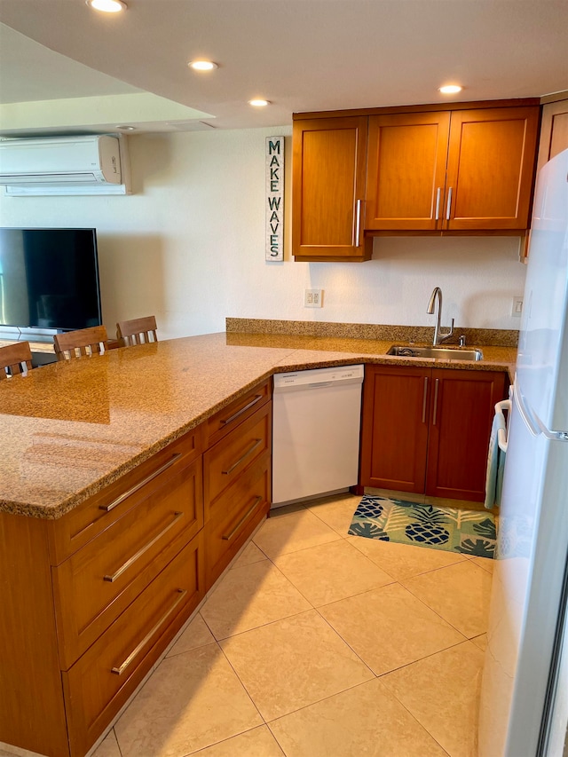 kitchen with sink, light stone countertops, light tile patterned floors, white appliances, and a wall mounted AC