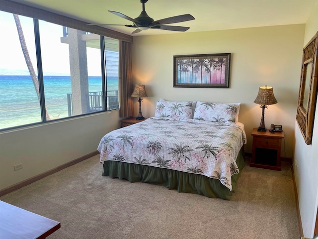 carpeted bedroom featuring ceiling fan, a water view, and multiple windows