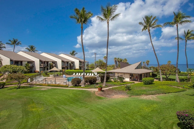 view of property's community with a swimming pool and a lawn