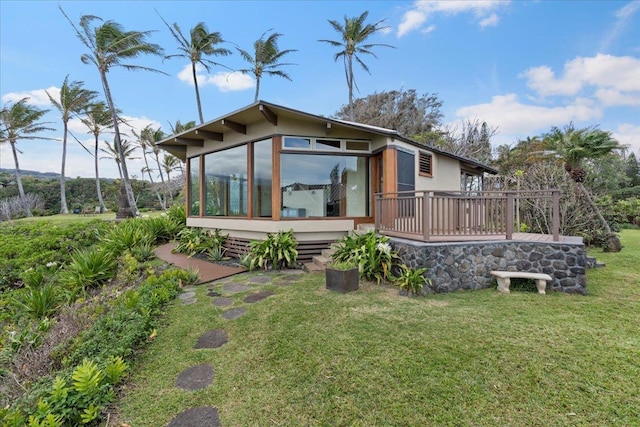 rear view of house featuring a wooden deck, a yard, and a sunroom