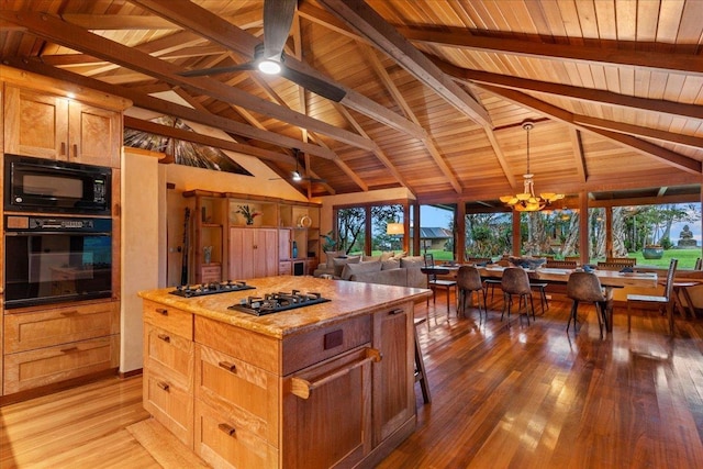 kitchen with beamed ceiling, black appliances, a center island, light hardwood / wood-style floors, and wood ceiling