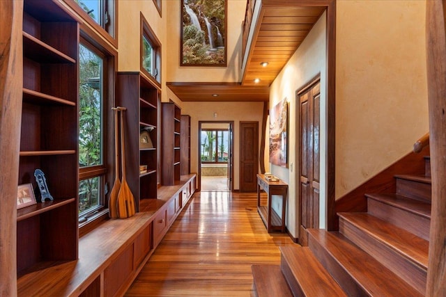 corridor with light hardwood / wood-style flooring, plenty of natural light, and wooden ceiling