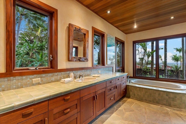 bathroom featuring backsplash, vanity, tiled bath, and wooden ceiling