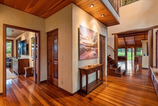 hall featuring a towering ceiling, hardwood / wood-style floors, and wooden ceiling