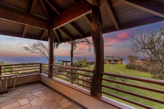 balcony at dusk featuring a water view