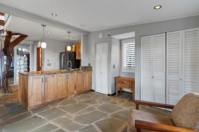 kitchen featuring hanging light fixtures, stainless steel refrigerator, and kitchen peninsula