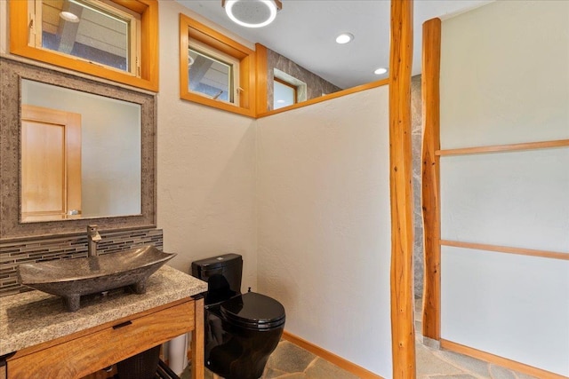 bathroom with vanity, toilet, and decorative backsplash