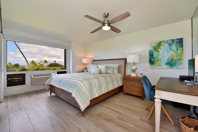 bedroom with a wall mounted air conditioner, light hardwood / wood-style flooring, and ceiling fan