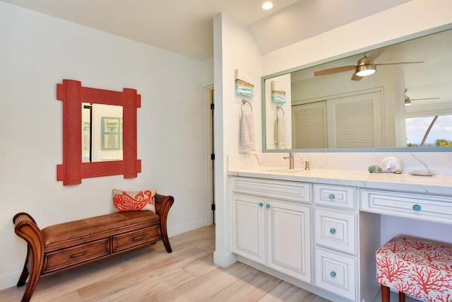 bathroom with ceiling fan, vanity, wood-type flooring, and vaulted ceiling