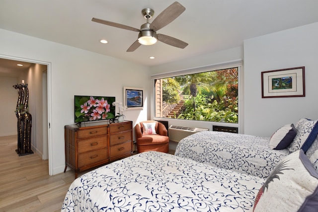 bedroom with an AC wall unit, ceiling fan, and light hardwood / wood-style flooring