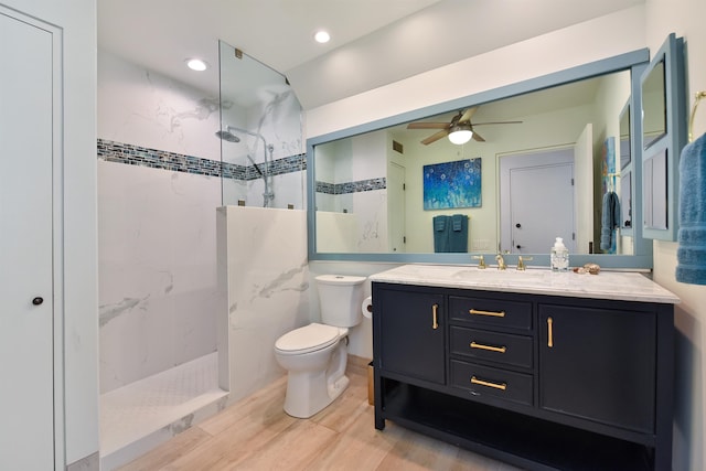 bathroom featuring hardwood / wood-style flooring, ceiling fan, tiled shower, and vanity