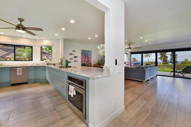 kitchen with ceiling fan, light wood-type flooring, light stone counters, kitchen peninsula, and stainless steel appliances