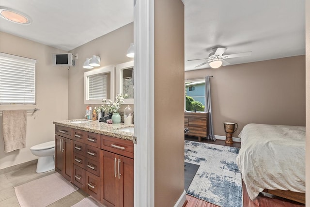 interior space with vanity, toilet, wood-type flooring, and ceiling fan