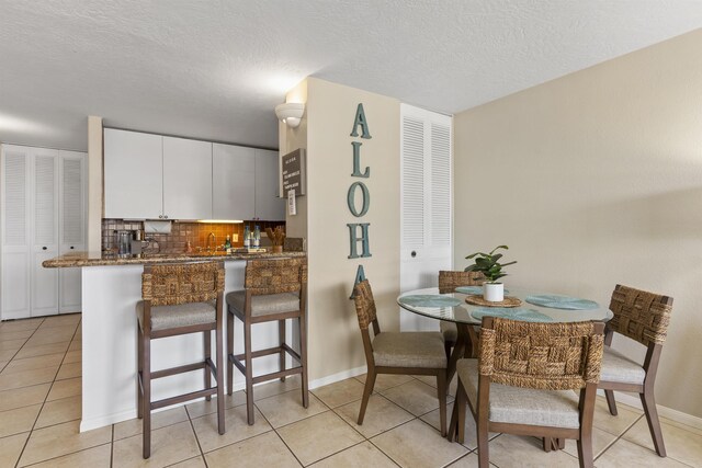 kitchen with white cabinetry, dark stone countertops, and decorative backsplash