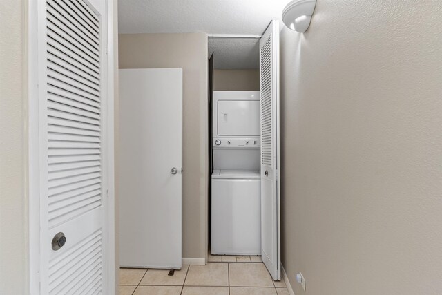 laundry area with light tile patterned floors and stacked washer and dryer